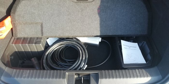 Sous le tapis de coffre, le bac pour le cable de recharge